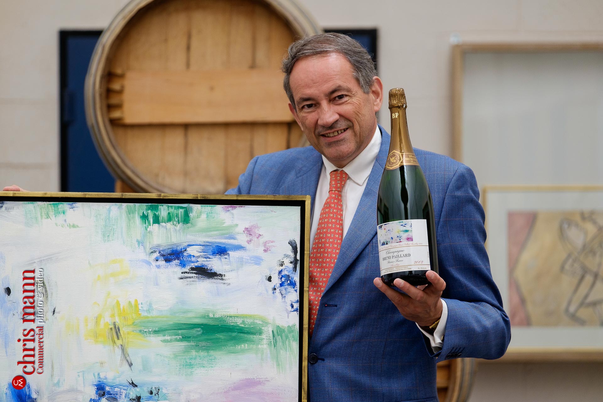 Bruno Paillard with a bottle of his champagne and the original painting that apperas on its label