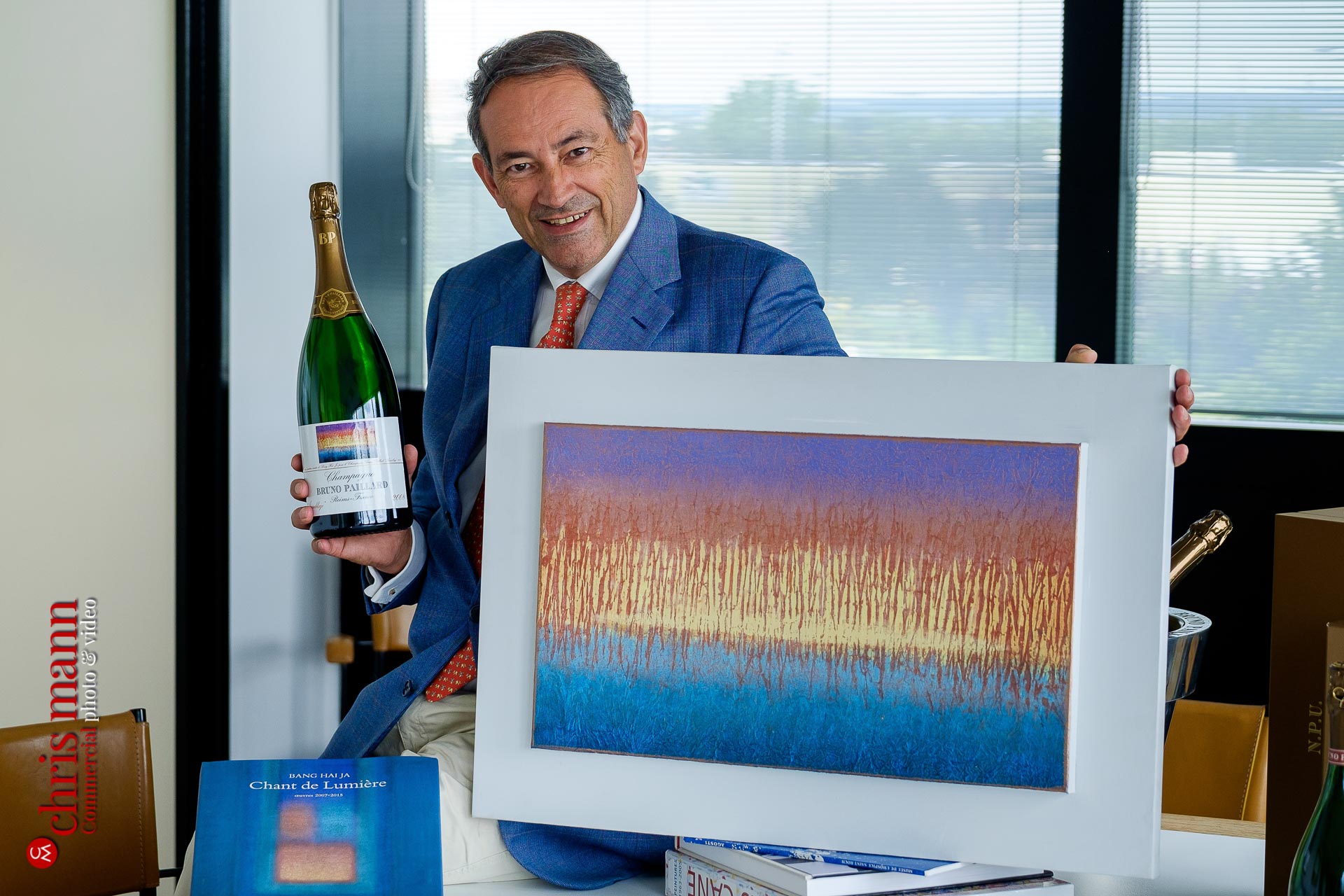 Bruno Paillard with a bottle of his champagne and the original painting that apperas on its label