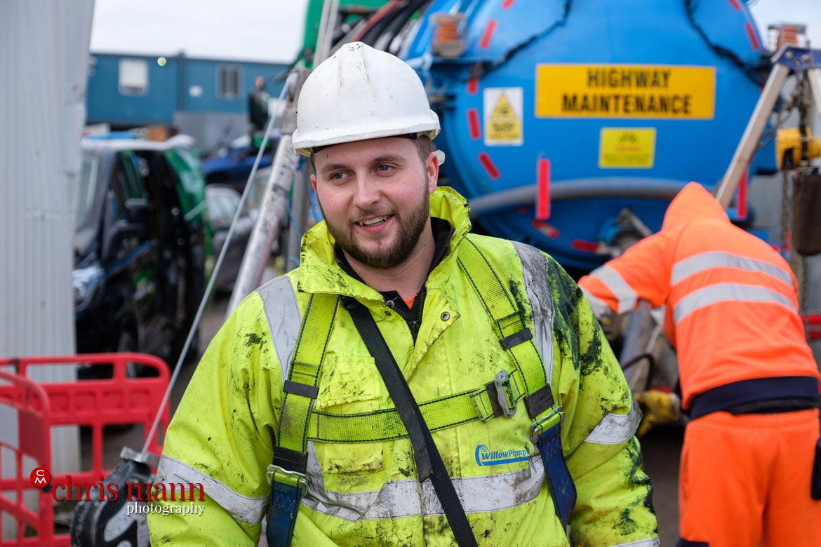 Engineer in hi-vis vest and hard hat smiles after completing his task